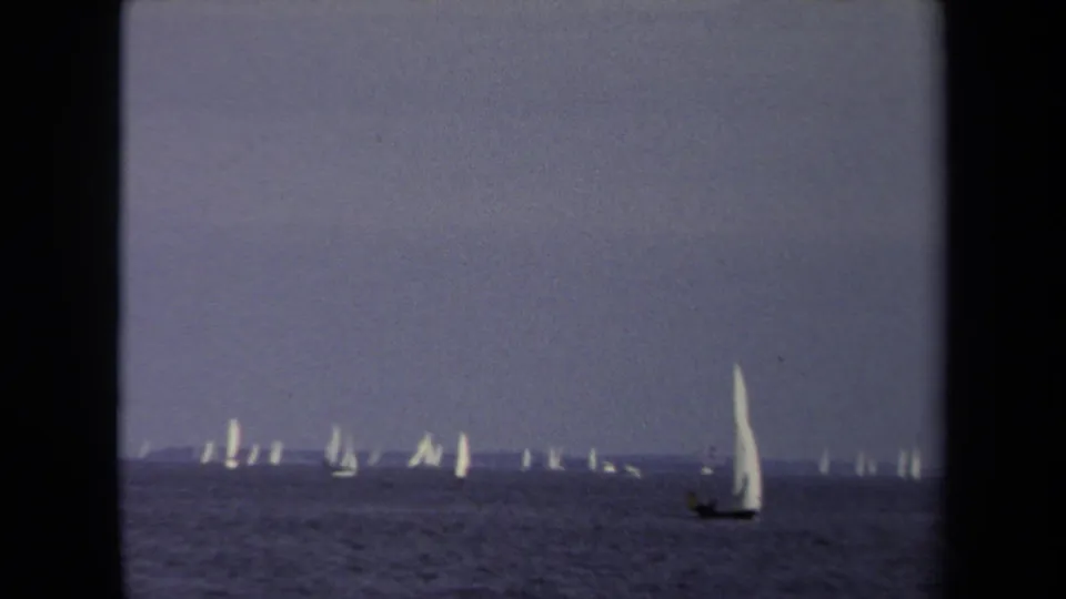 1970 Annapolis 8mm frame showing many distant sailboats on open water, with one larger white sail nearer the foreground.