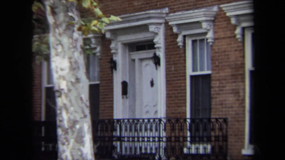 Tight Annapolis frame from 1970 showing the townhouse entrance, black iron fence, tall window, and pale street tree in front.