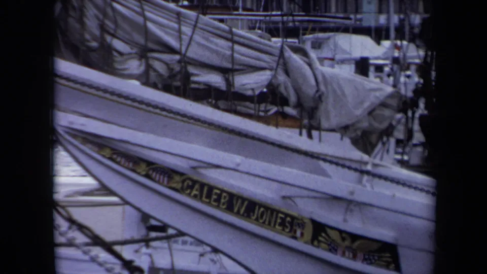 1970 Annapolis marina frame with the Caleb W. Jones nameboard, rigging, canvas covers, and nearby docked boats in soft 8mm color.