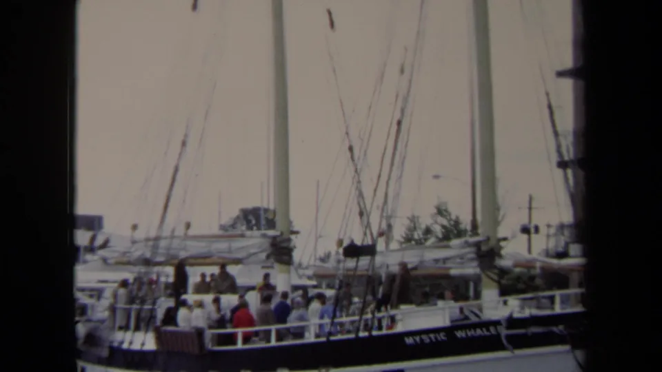 In Annapolis in 1970, people stand on the deck of the Mystic Whaler sailboat while it is docked at a marina.