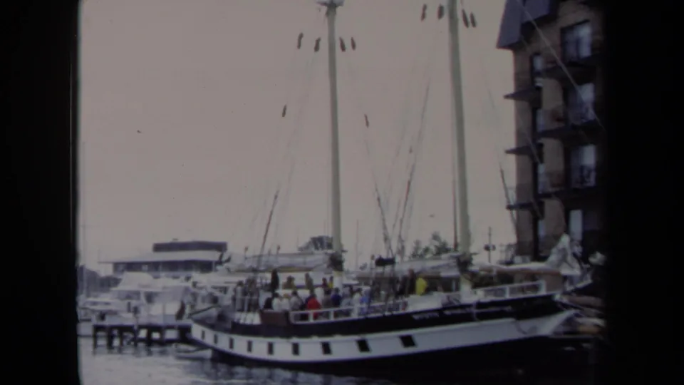 A wider 1970 Annapolis marina view shows the Mystic Whaler docked, people clustered on deck, and rigging set against a pale sky.