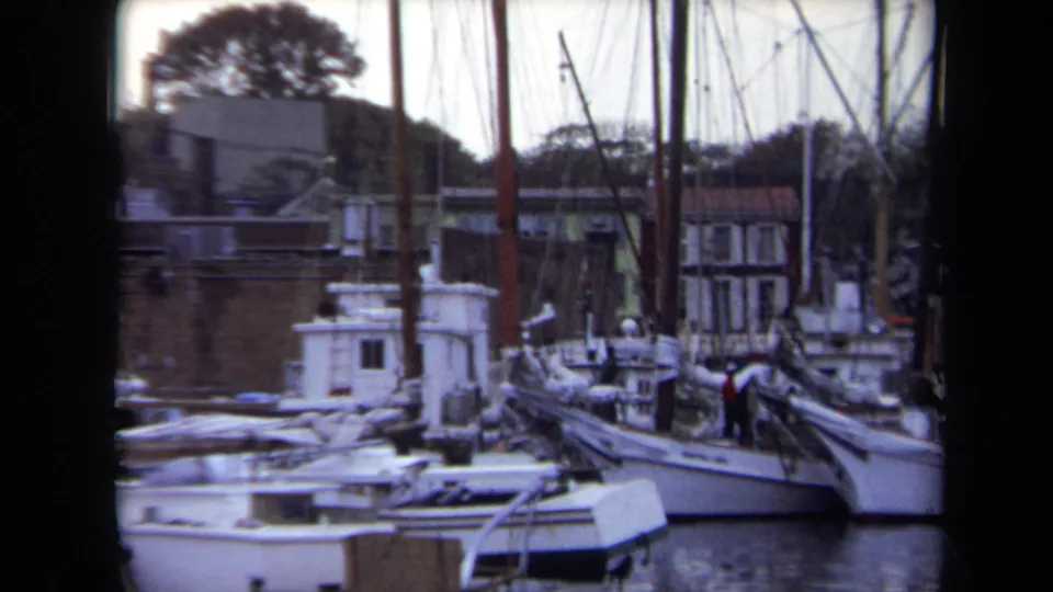 1970 Annapolis harbor view of small boats and sailboats crowded near brick waterfront structures, with people visible aboard.