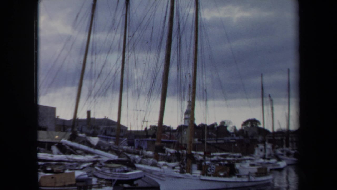 1970 Annapolis 8mm frame showing sailboats moored near docks, with many masts against a cloudy waterfront sky.