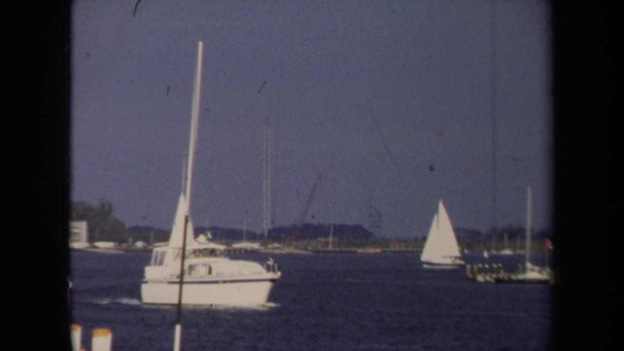 1970 Annapolis boating scene with a large sailboat in the foreground and another sailboat farther across the water.