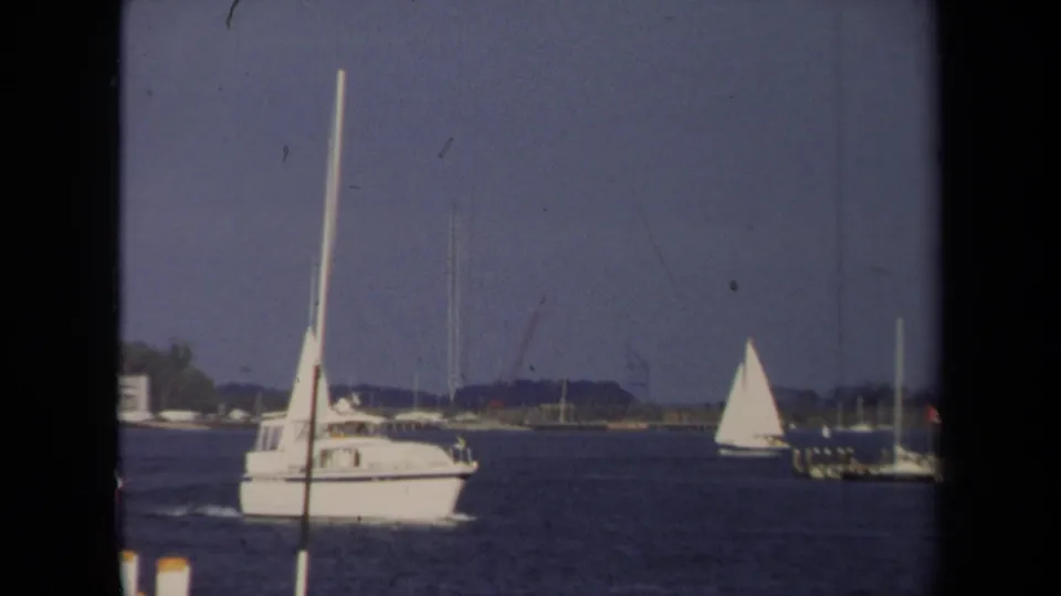 1970 Annapolis boating scene with a large sailboat in the foreground and another sailboat farther across the water.
