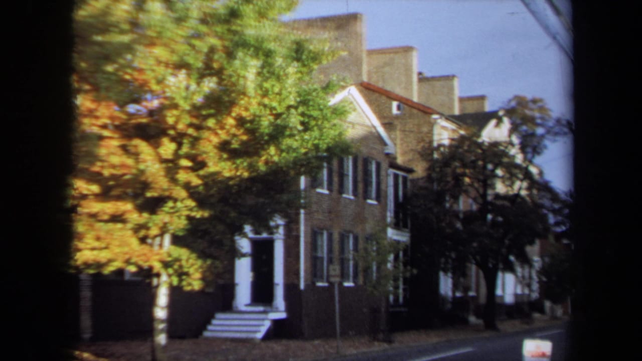1970 Annapolis residential street view with brick homes, white entry steps, windows, a small sign, and autumn foliage.