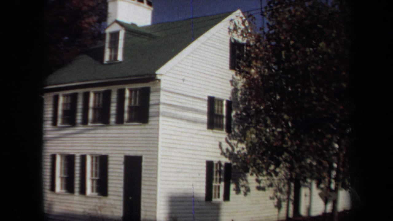 Two-story white house with black shutters and a tree along the right side of the frame.