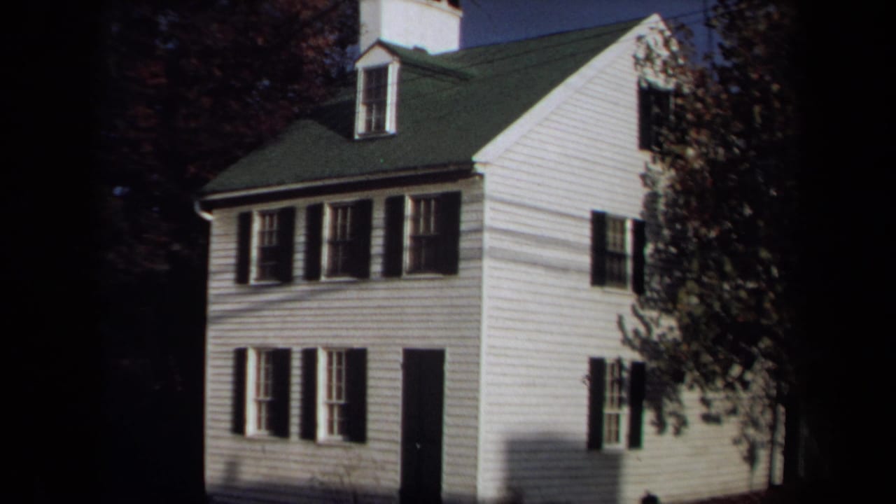 Closer 1970 Annapolis 8mm view of the white clapboard house, showing black shutters, dormer, green roof, and autumn foliage.