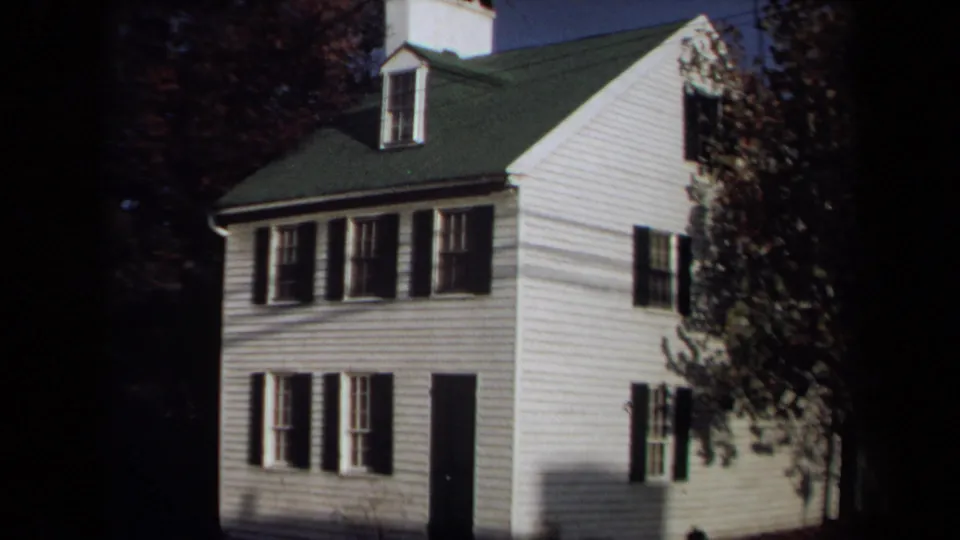 Closer 1970 Annapolis 8mm view of the white clapboard house, showing black shutters, dormer, green roof, and autumn foliage.
