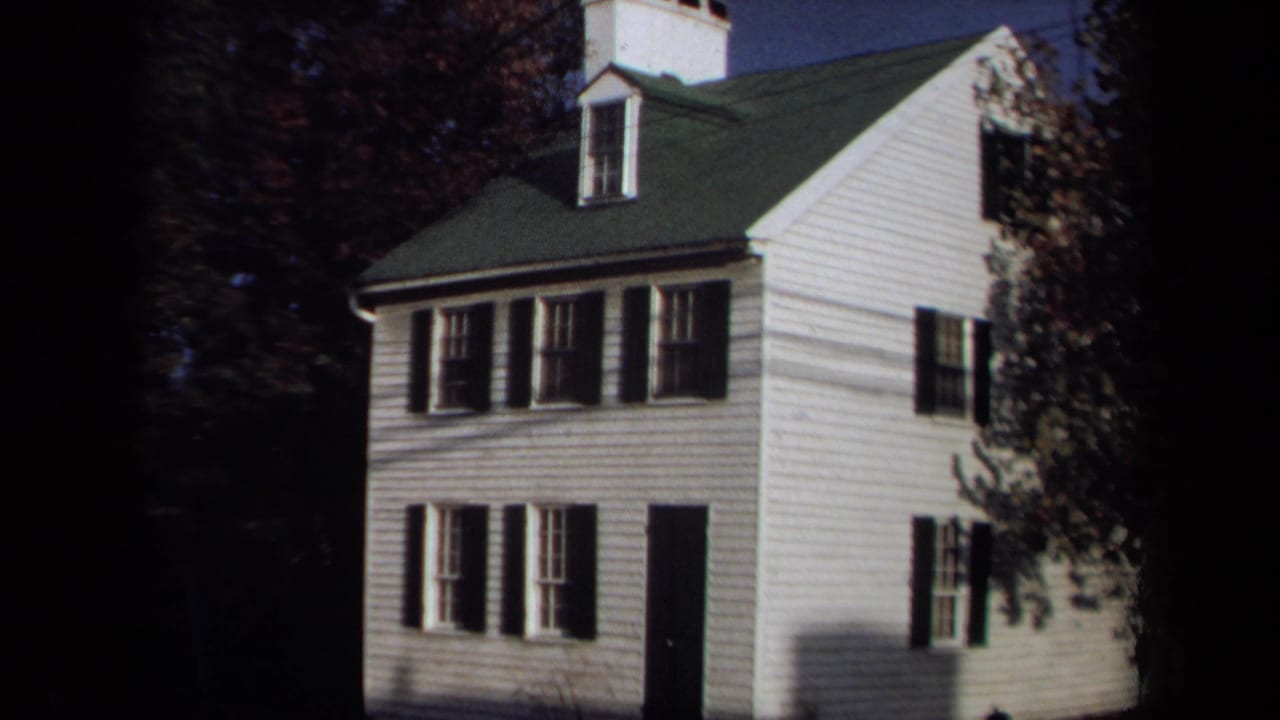 Final 1970 Annapolis frame holds on the white house exterior with black shutters, a green roof, dark doorway, and autumn trees.