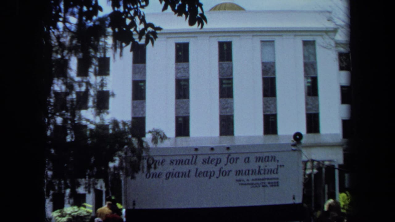 Quote banner on a white building with small people visible near the lower edge.