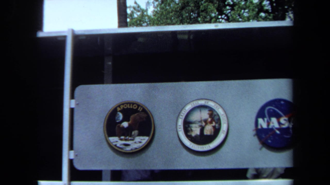 Apollo mission patches and NASA logo displayed on an exhibit panel with a visitor partly visible.