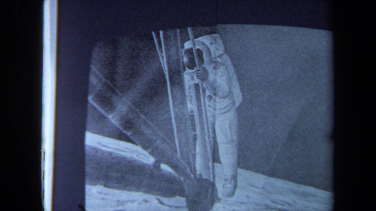 Astronaut on a television screen, framed by dark borders and blue-tinted film grain.