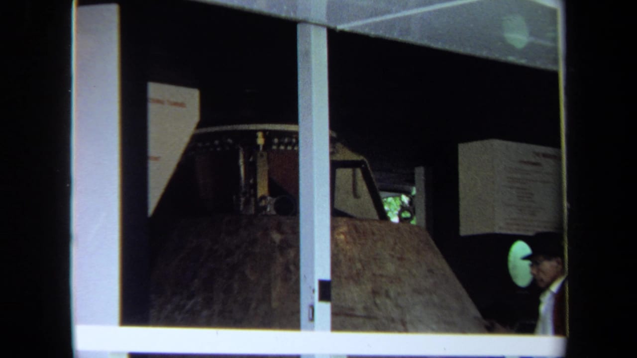 Scale model of a lunar module inside a display area, with an adult visitor at the right edge.