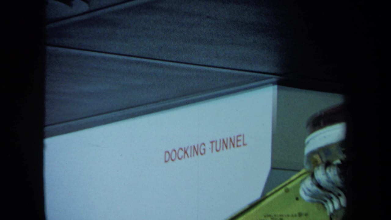 White wall marked DOCKING TUNNEL beside industrial equipment in a dark interior.