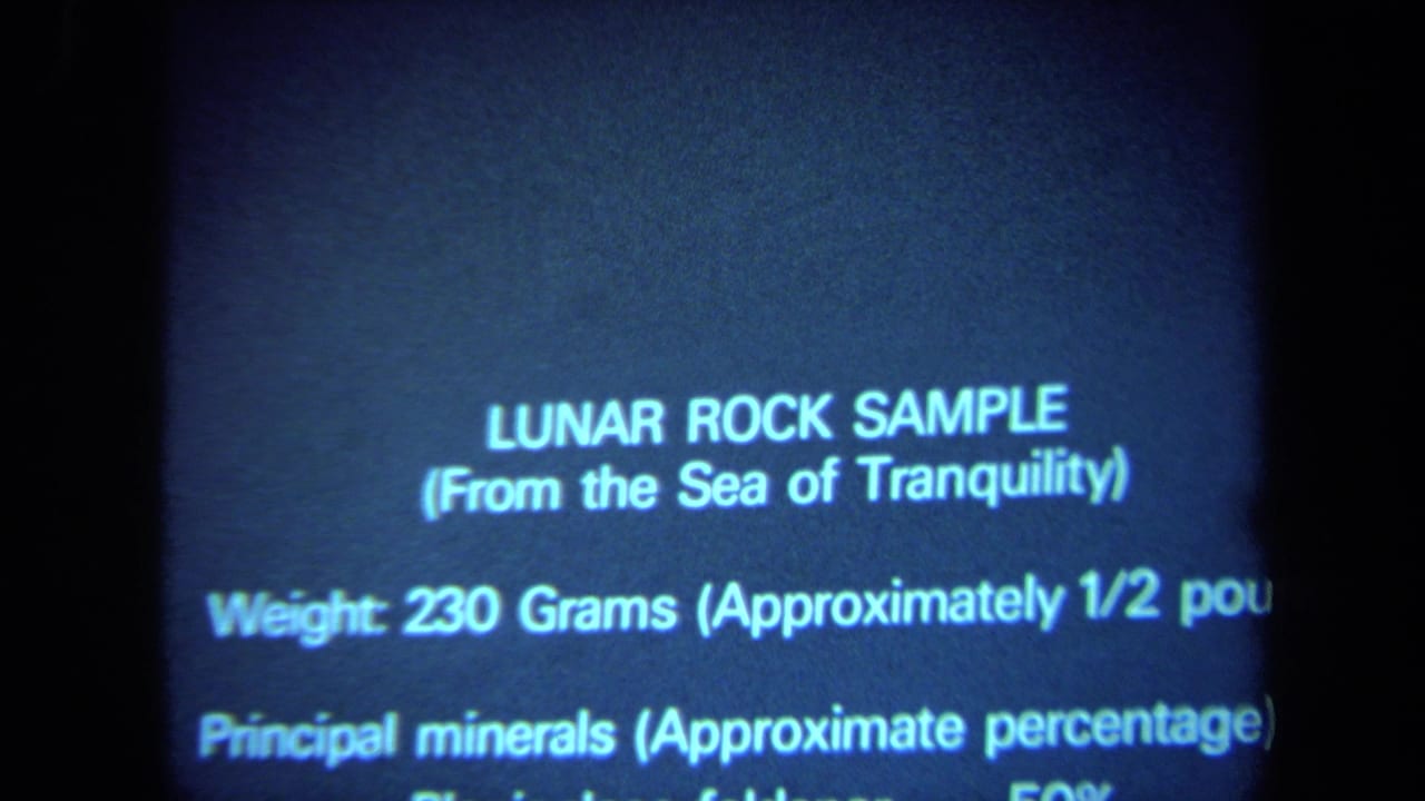 Projected slide text for a lunar rock sample, partially cropped in a blue-toned frame.