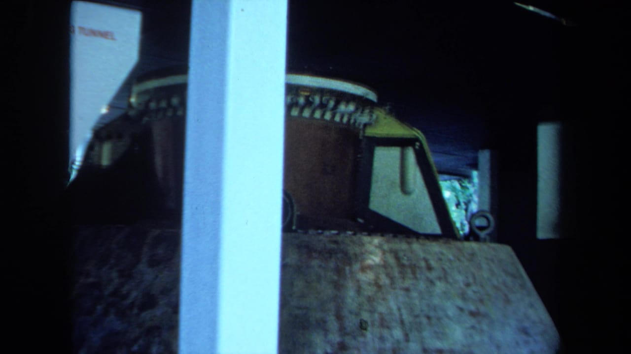 1970 California 8mm frame showing the outside of a rocket or capsule display, with a windowed section and dark surrounding space.