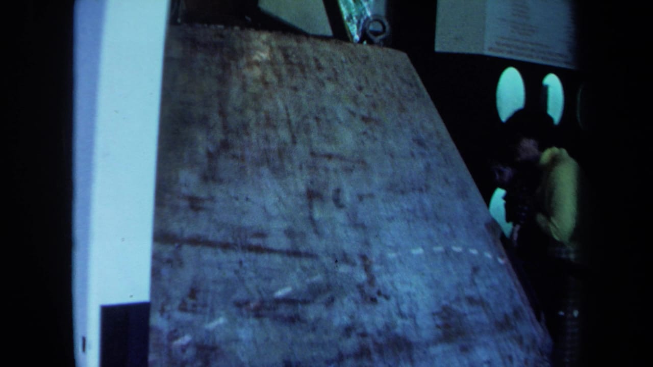 Concrete-like slab dominates the frame beside a dark vehicle with rounded windows and a person at right.
