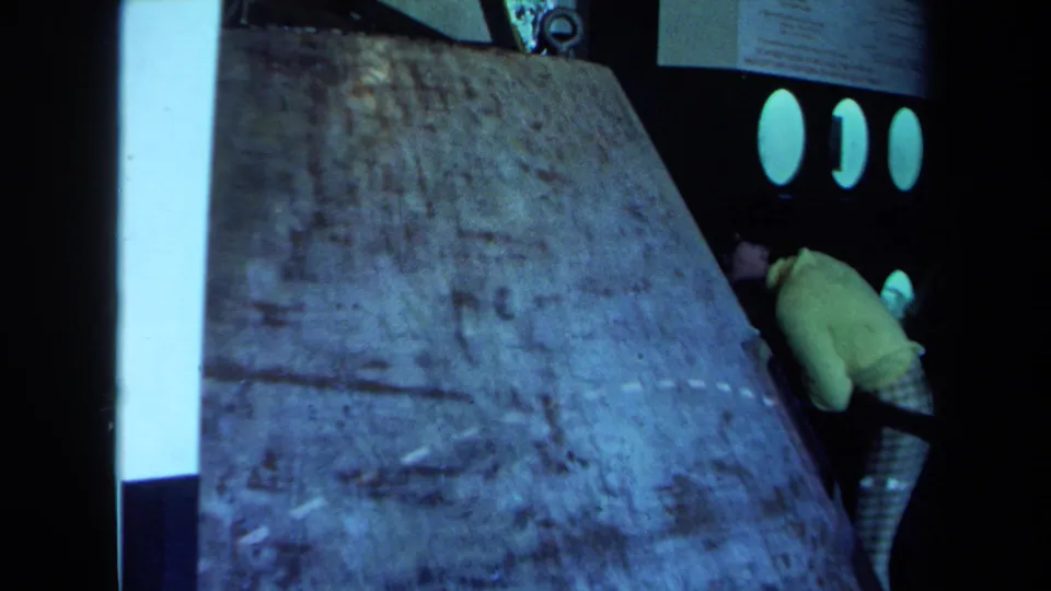 Final frame shows the concrete-like slab beside the dark bus or vehicle, with a person in yellow still partly visible at the right.