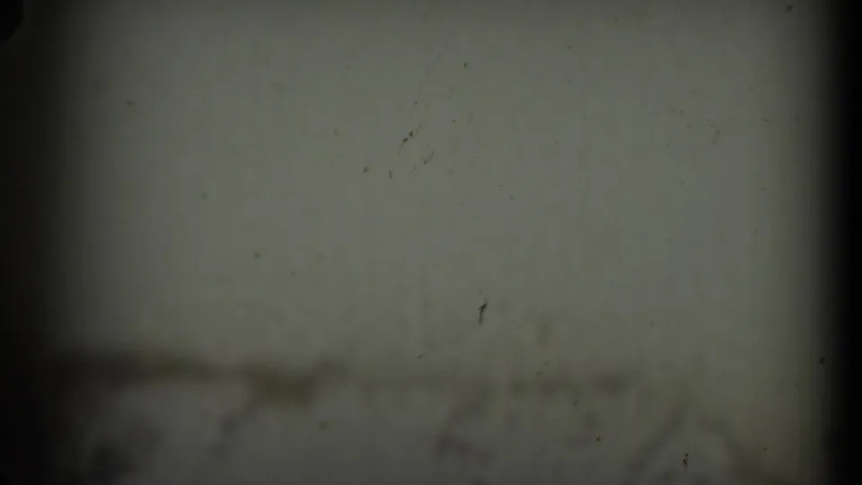 A dark 8mm frame shifts away from the rocket display to a dim, soft-focused sign or pale surface, with heavy vignette at the edges.