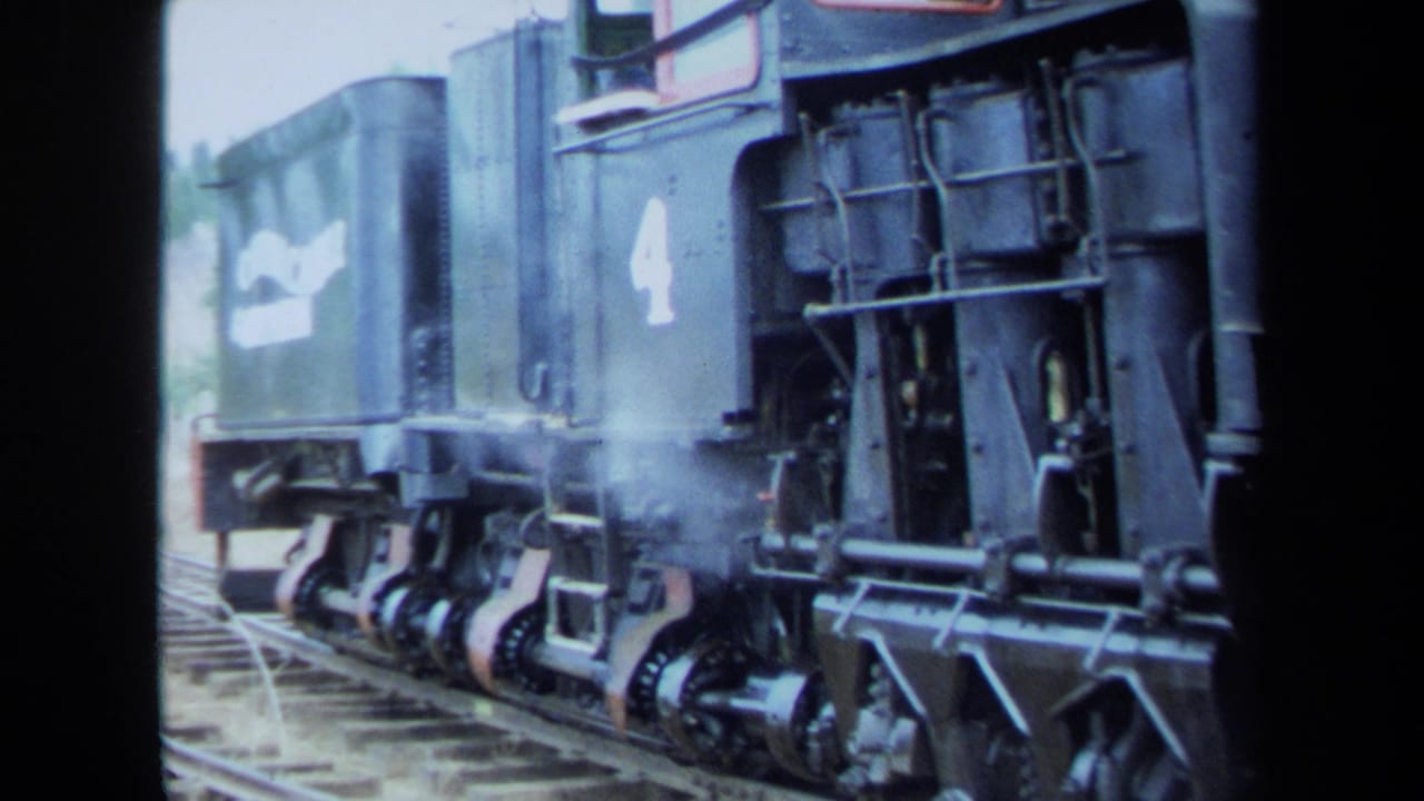 Close view of a black steam locomotive marked 4 releasing steam beside the track during the 1970 California home movie.
