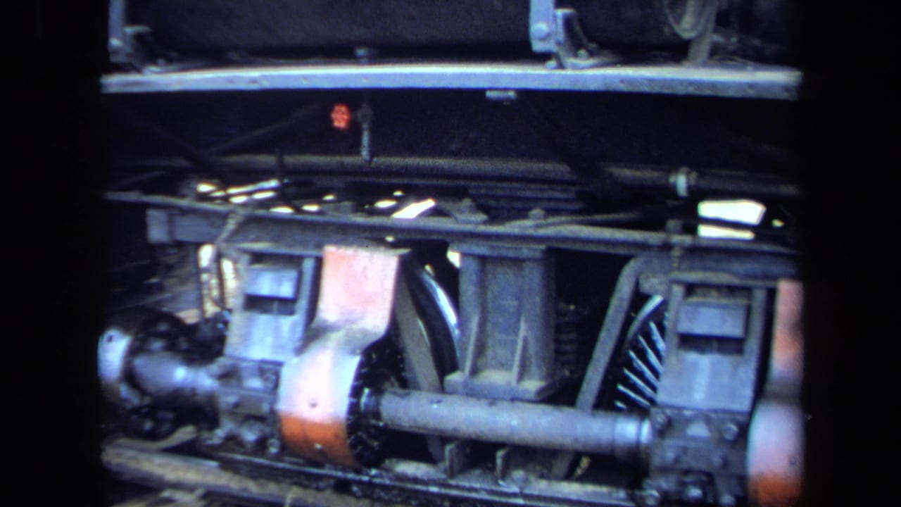 1970 8mm California frame showing locomotive wheels, axle, rods, and undercarriage components beneath a dark side panel.