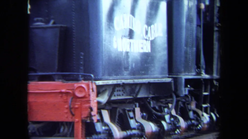 1970 California 8mm frame showing readable white tender lettering over locomotive wheels and red metalwork.