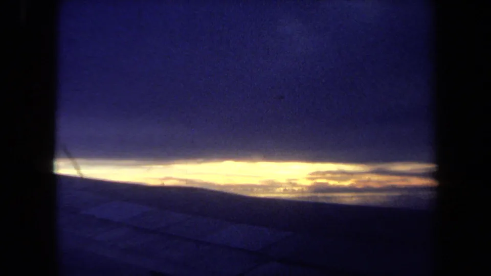 1970 California 8mm view of a bright horizon line under deep blue clouds, with dark framing suggesting a window or film gate.