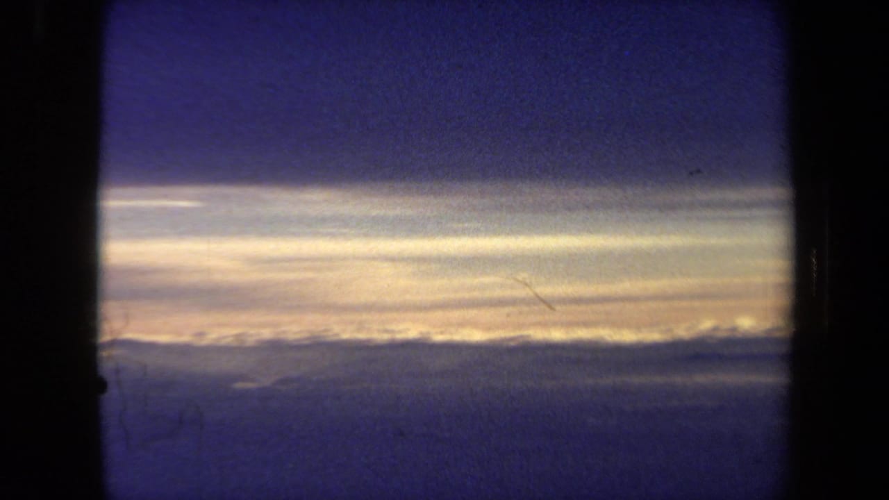 Dark airplane window frame over a blue sunset sky and cloud horizon.