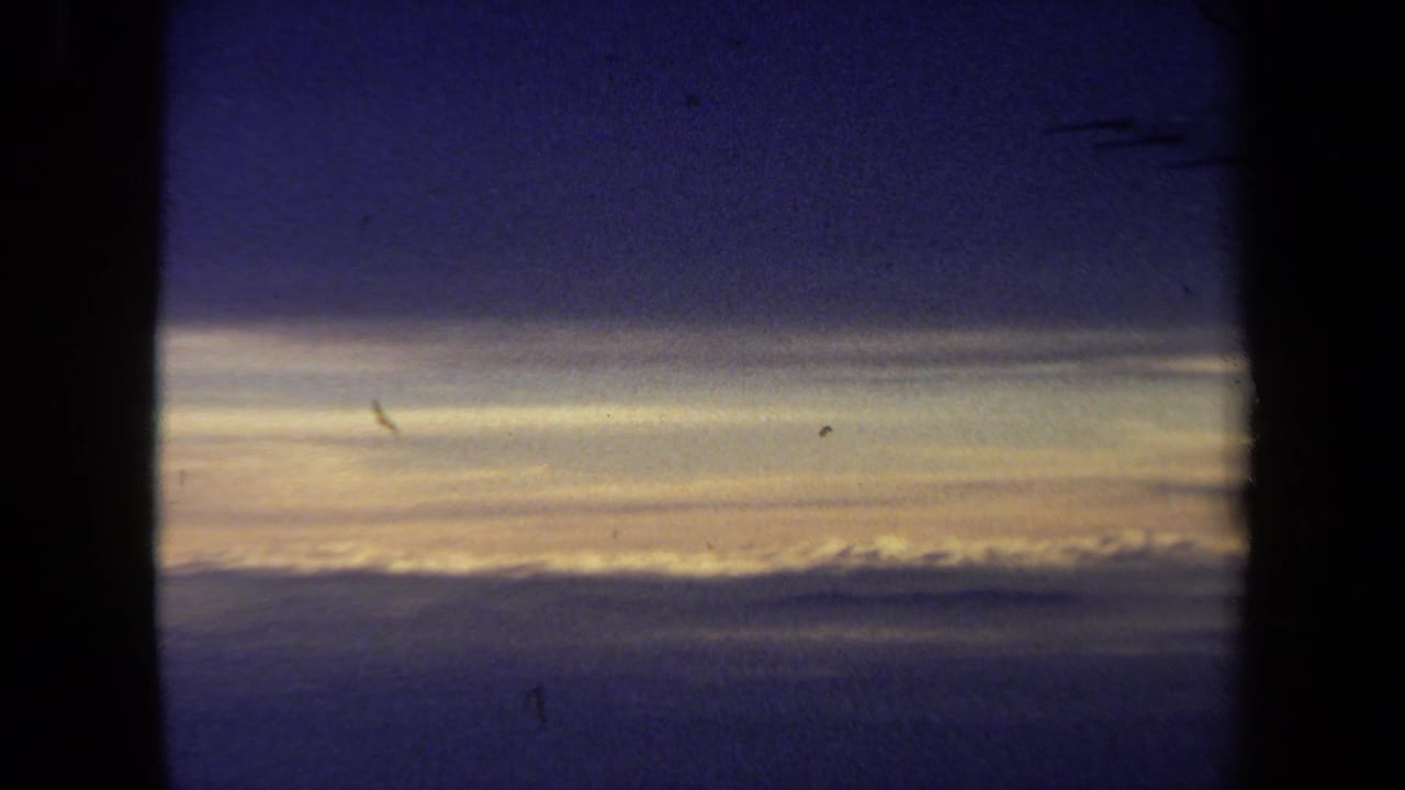 Blue sky and golden cloud horizon divided by a dark airplane window post.