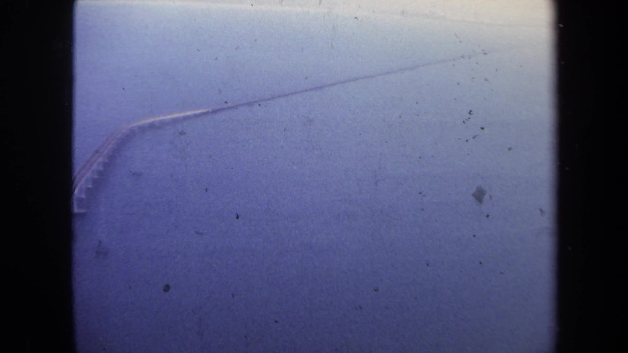 1970 8mm travel footage from the Washington, DC area showing a distant bridge or causeway over water through soft blue film grain.