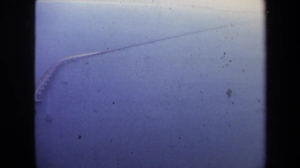 1970 8mm travel footage from the Washington, DC area showing a distant bridge or causeway over water through soft blue film grain.