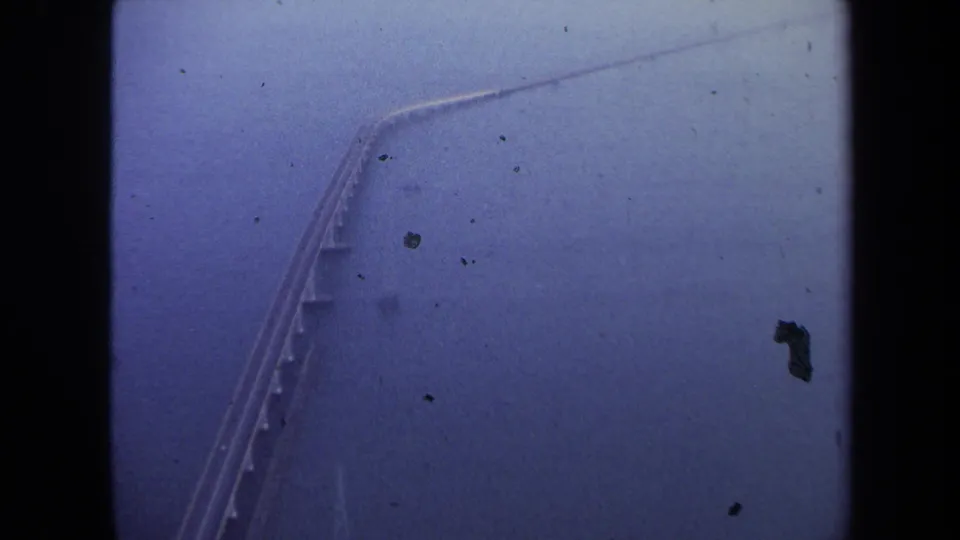 Elevated 1970 home-movie view of a long bridge over water, likely from the Washington, DC travel sequence, with visible film grain and fading.