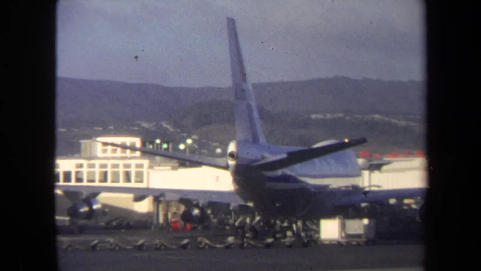 Large commercial aircraft at a Washington, DC terminal in 1970, seen from a distance with workers and baggage equipment on the ramp.