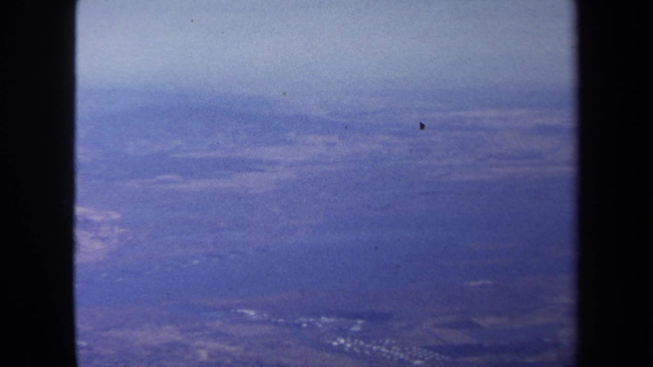 Aerial landscape under hazy sky with a dark vertical border through the frame.