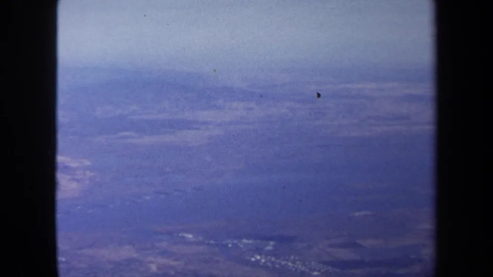 Blue-hued 1970 aerial view over distant land near Washington DC, divided by a dark vertical frame or window edge.