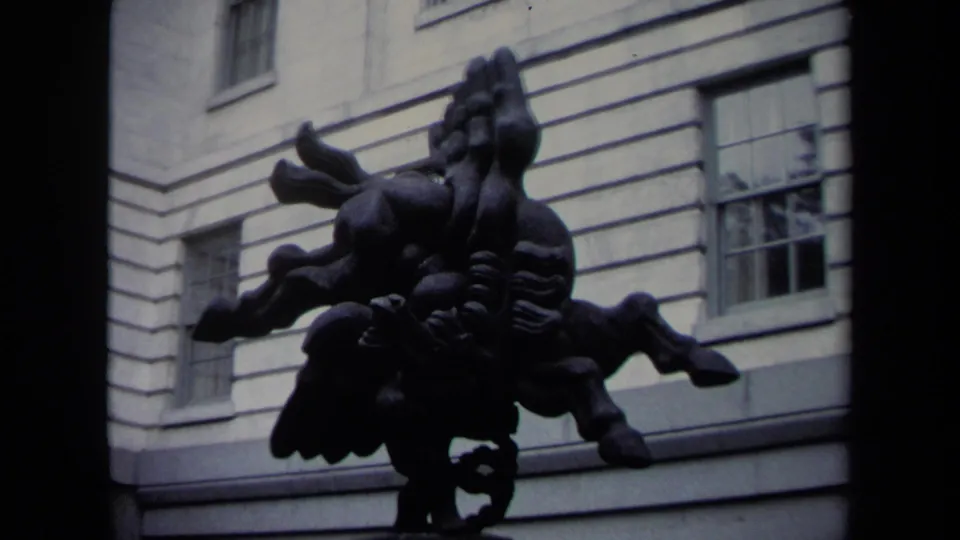 1970 Washington DC 8mm view of the dark sculptural form with hooves and curved shapes before a pale stone building.