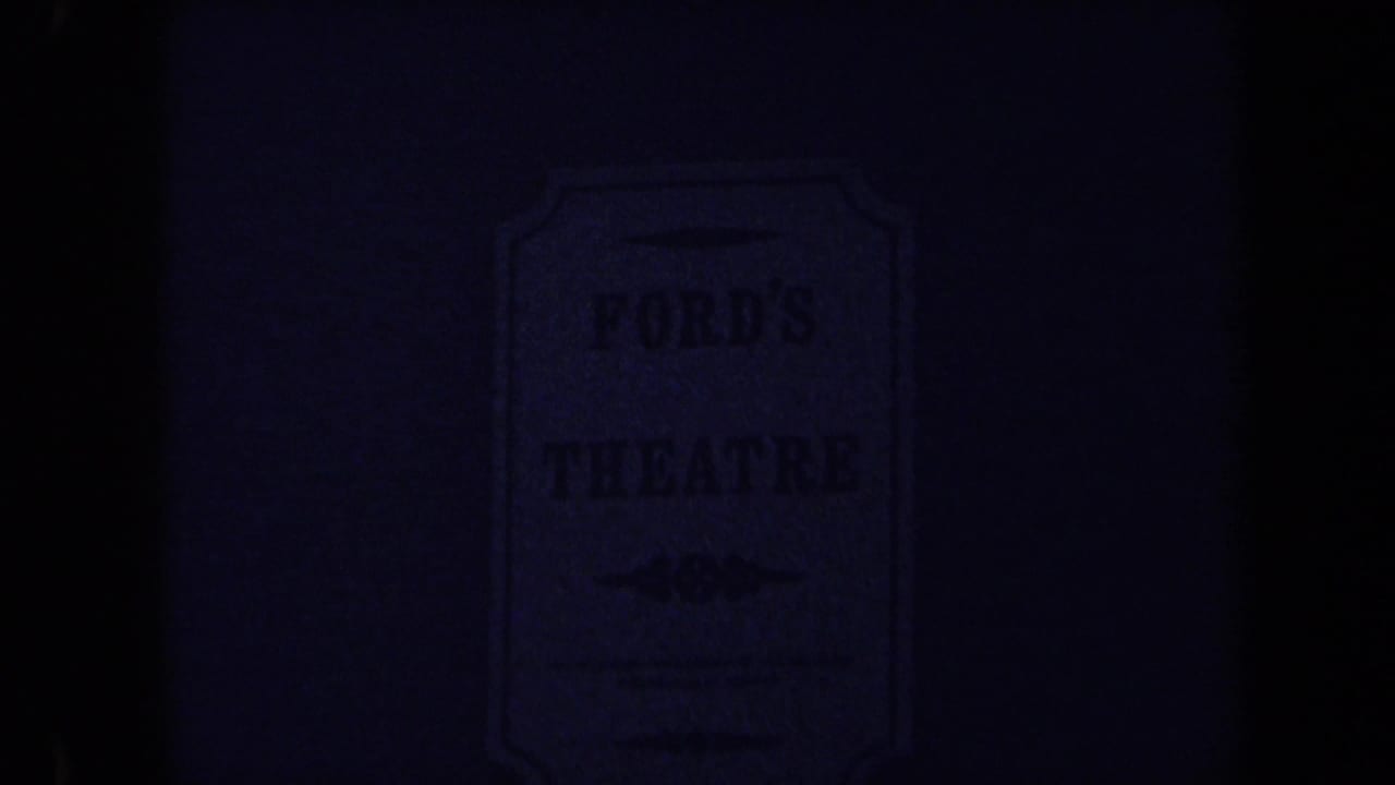 1970 8mm frame in Washington DC showing a dim, partially obscured Ford's Theatre sign on a brick wall.