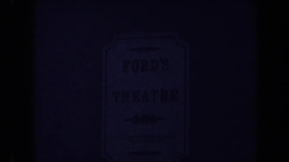 1970 8mm frame in Washington DC showing a dim, partially obscured Ford's Theatre sign on a brick wall.