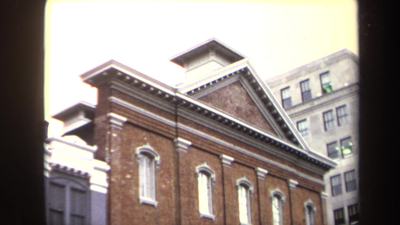 1970 Washington, DC home-movie view of Ford's Theatre facade, with red brick, white accents, and taller buildings behind it.