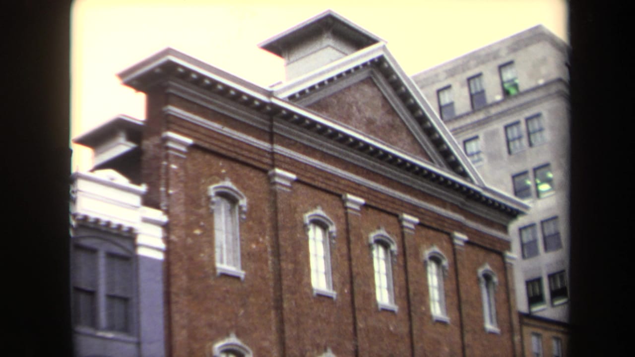 Ford's Theatre facade seen through dark vertical borders with city buildings in the background.