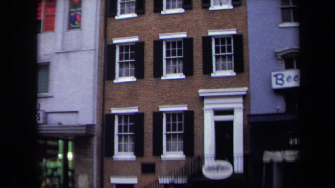 1970 Washington, DC rowhouse facade with black shutters, white doorway trim, neighboring shopfronts, and partial Beef signage.