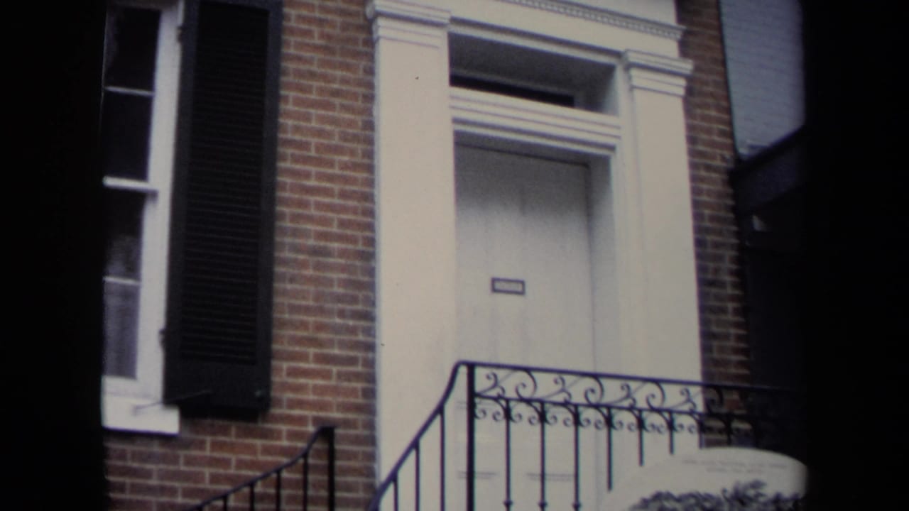 1970 Washington, DC frame with a brick building entrance, white door surround, black shutter, steps, and decorative iron railing.