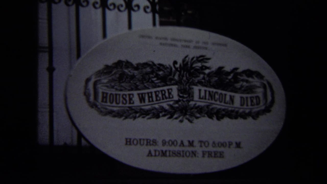 Darker view of the House Where Lincoln Died oval sign behind ironwork.