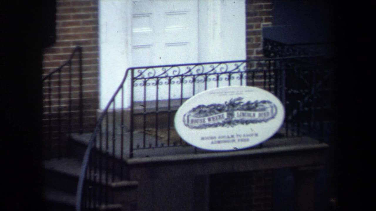 Washington, DC historic-site exterior showing a white door, brick wall, iron railing, steps, and the House Where Lincoln Died sign.