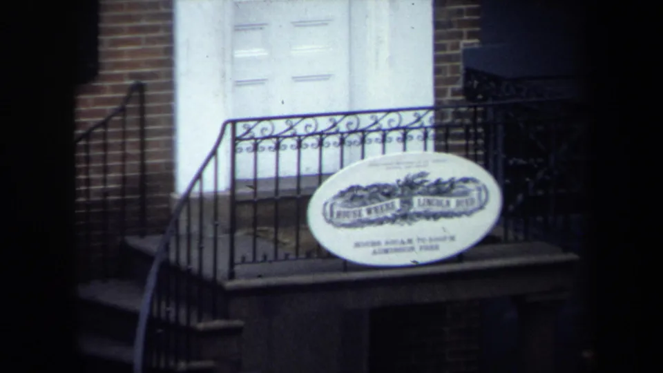 Washington, DC historic-site exterior showing a white door, brick wall, iron railing, steps, and the House Where Lincoln Died sign.