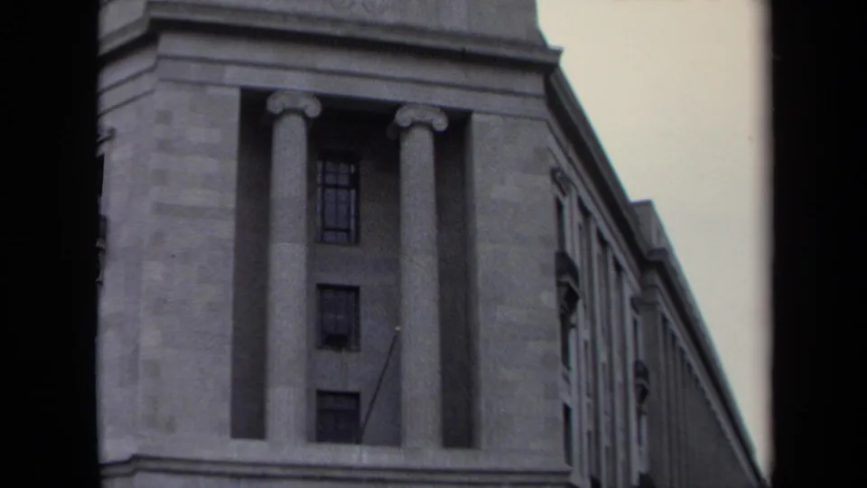 1970 Washington, DC 8mm frame showing the upper facade of a large classical stone building with columns and rows of windows.