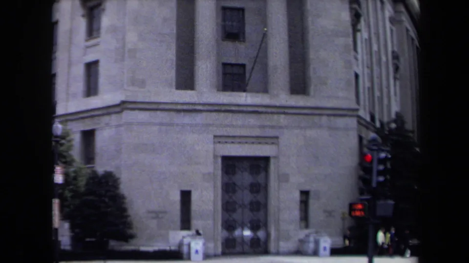 1970 Washington, DC 8mm frame showing the lower facade, column bases, entrance area, traffic light, and small pedestrians on the sidewalk.