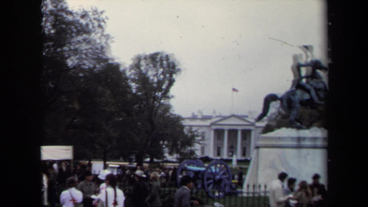 1970 Washington, DC home-movie frame showing visitors near a cannon and equestrian statue with the White House in the background.