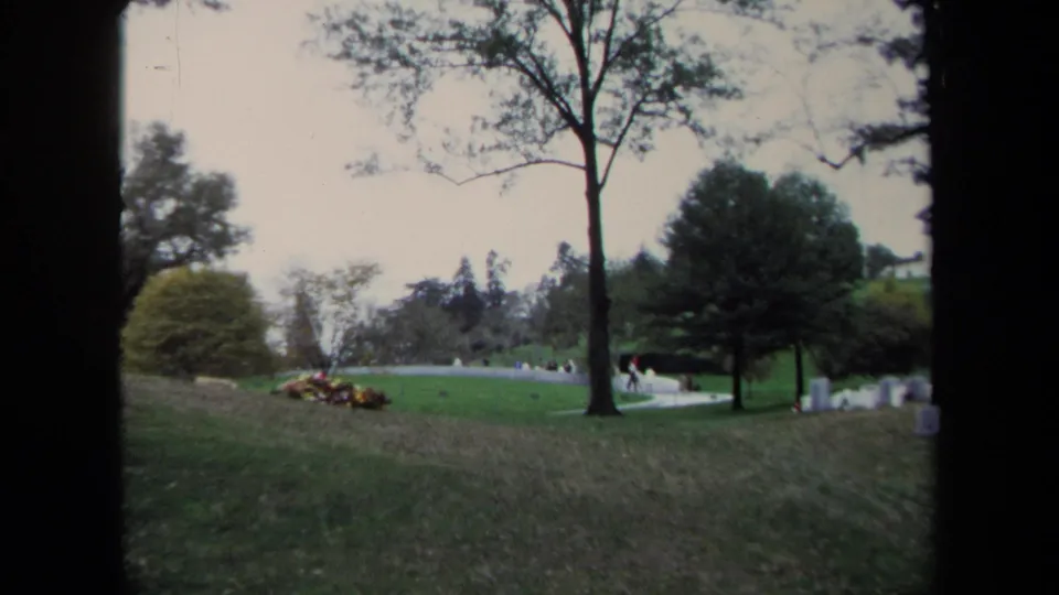 1970 Washington DC park scene showing a green slope, large trees, distant people near a curving path, and small marker-like objects.